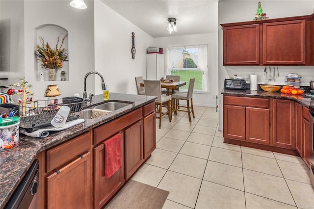 kitchen featuring dishwasher, dark stone countertops, light tile patterned floors, and sink