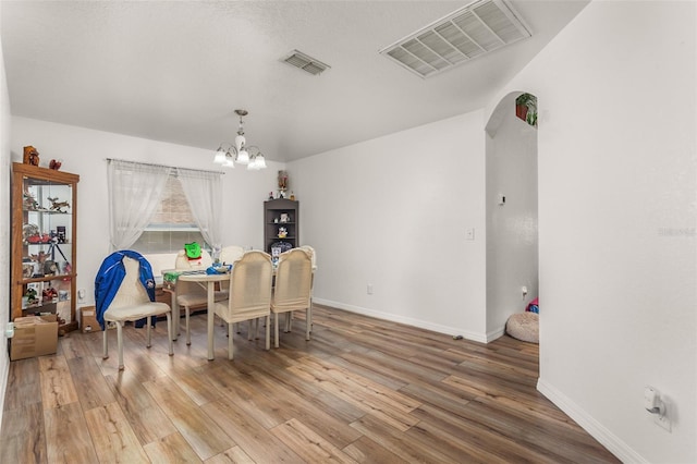 dining space with visible vents, baseboards, an inviting chandelier, and wood finished floors