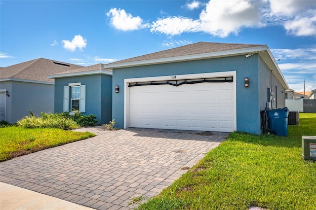 ranch-style house with a garage, a front lawn, and central air condition unit