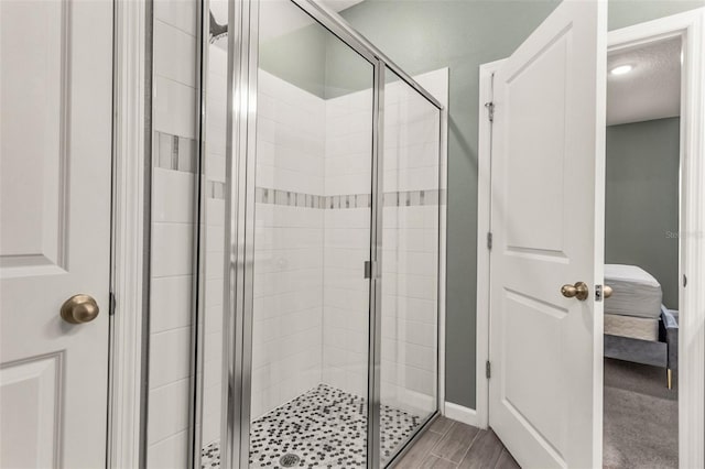 bathroom with a shower with shower door and hardwood / wood-style floors