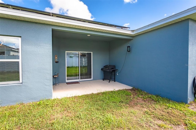 property entrance featuring a lawn and a patio area