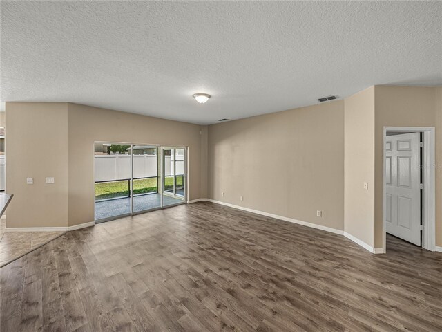 unfurnished room featuring dark wood-type flooring and a textured ceiling