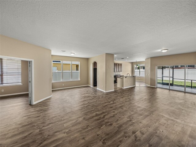 unfurnished living room featuring a textured ceiling, dark hardwood / wood-style floors, and sink