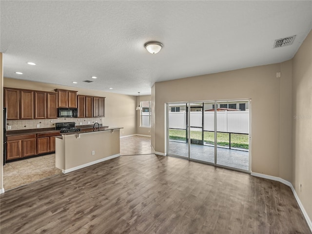 kitchen featuring light hardwood / wood-style floors, sink, black appliances, decorative backsplash, and a textured ceiling