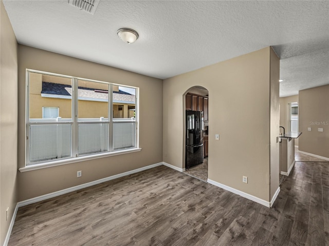 empty room with dark wood-type flooring and a textured ceiling