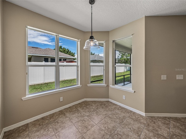 unfurnished dining area with light tile patterned floors and a textured ceiling