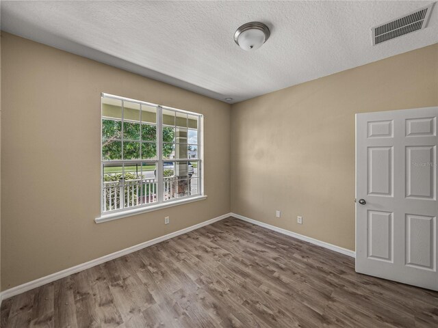 spare room featuring a textured ceiling and dark hardwood / wood-style floors