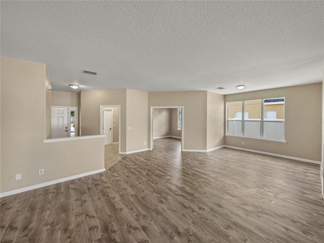 unfurnished living room featuring hardwood / wood-style flooring and a textured ceiling