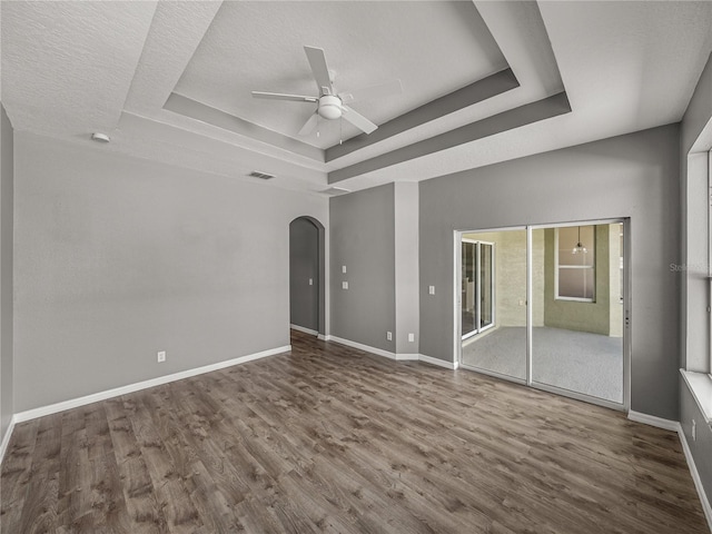 unfurnished bedroom featuring a raised ceiling, a textured ceiling, ceiling fan, and hardwood / wood-style floors