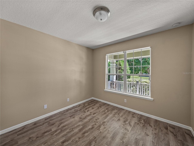 unfurnished room with wood-type flooring and a textured ceiling