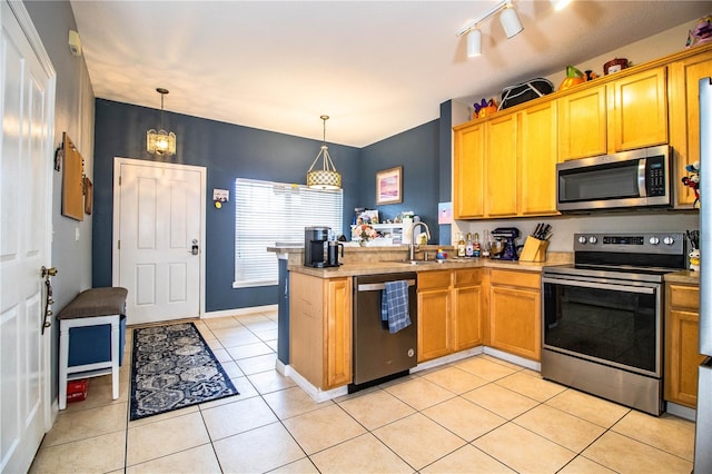 kitchen with appliances with stainless steel finishes, kitchen peninsula, sink, and decorative light fixtures