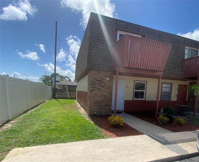 view of front of house featuring a front yard, mansard roof, brick siding, and a shingled roof