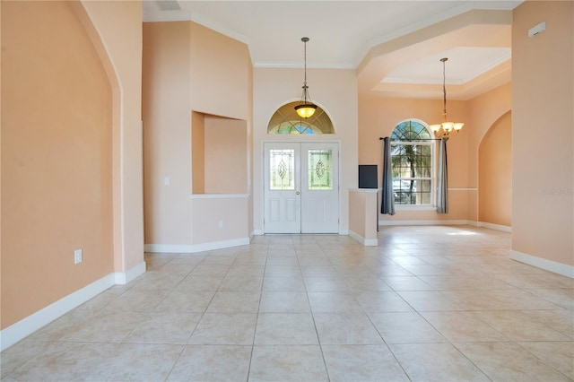 tiled foyer entrance featuring a raised ceiling, a chandelier, and ornamental molding