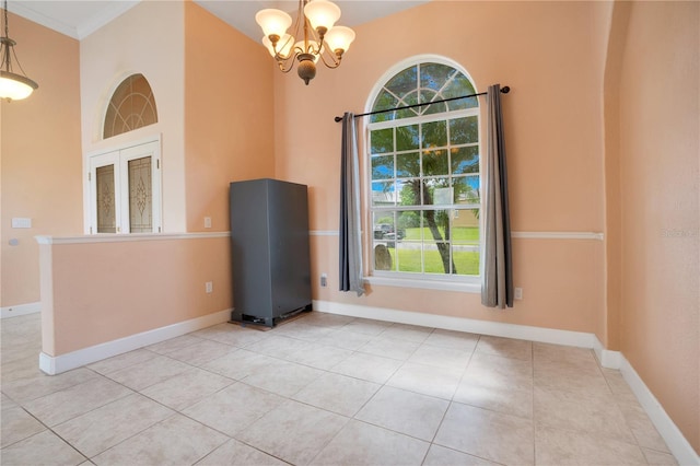 unfurnished room with crown molding, light tile patterned floors, and an inviting chandelier