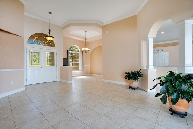 entrance foyer with a chandelier, crown molding, and ornate columns