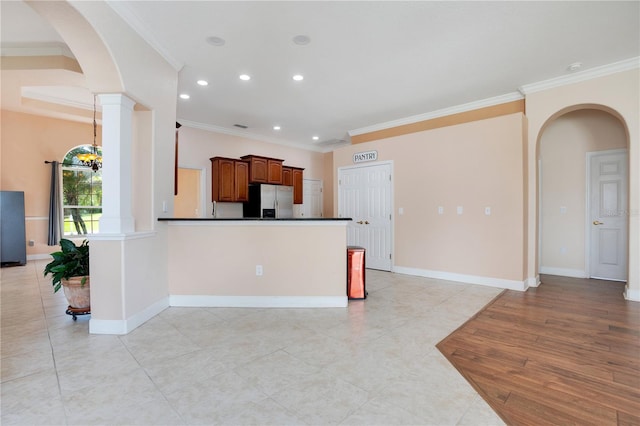 kitchen with ornamental molding, light tile patterned floors, kitchen peninsula, an inviting chandelier, and stainless steel refrigerator with ice dispenser