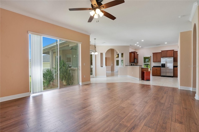 unfurnished living room featuring light wood-type flooring, ceiling fan, and ornamental molding