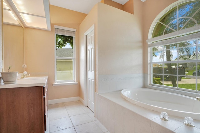 bathroom featuring tile patterned flooring, a relaxing tiled tub, and vanity