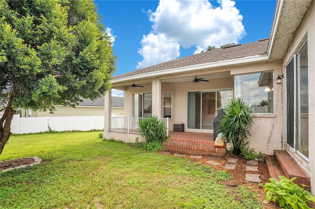 back of house featuring a lawn and ceiling fan