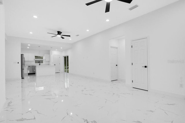 unfurnished living room featuring ceiling fan and sink