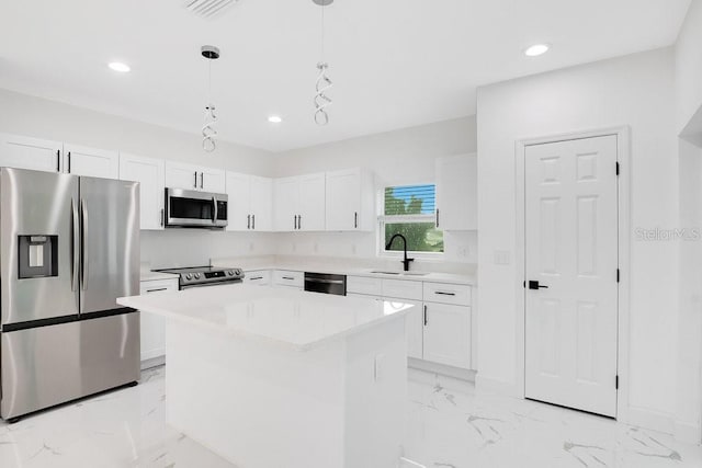 kitchen featuring a kitchen island, white cabinetry, appliances with stainless steel finishes, decorative light fixtures, and sink