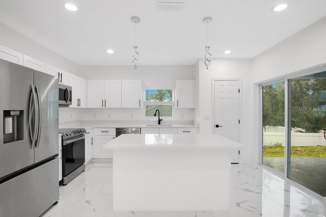 kitchen featuring stainless steel appliances, a center island, white cabinets, sink, and pendant lighting