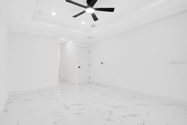 empty room featuring ceiling fan and a raised ceiling