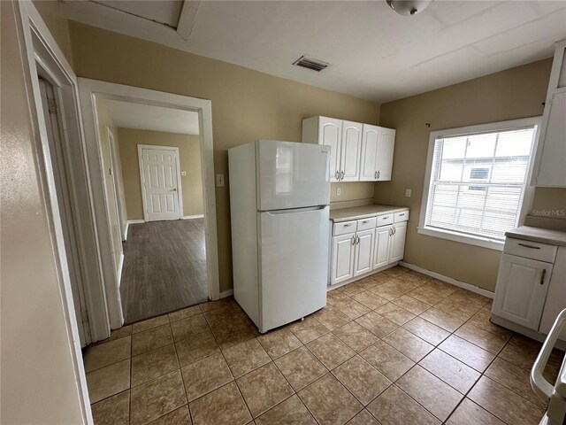 kitchen with light wood-type flooring, white cabinets, and white fridge