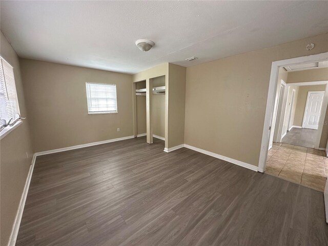 unfurnished bedroom with a closet, a textured ceiling, and dark hardwood / wood-style floors