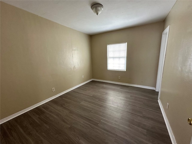 empty room featuring baseboards and dark wood-type flooring