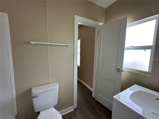 bathroom featuring baseboards, toilet, wood finished floors, and vanity