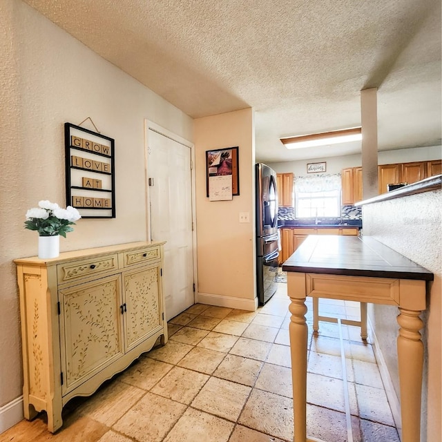 kitchen with a textured ceiling and stainless steel fridge with ice dispenser