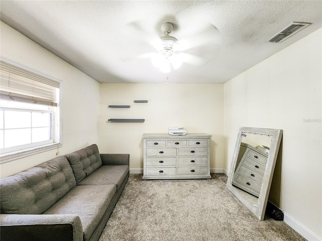 sitting room with light colored carpet, a textured ceiling, and ceiling fan