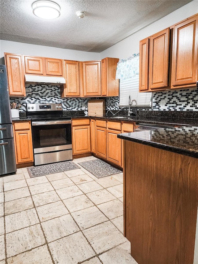 kitchen featuring decorative backsplash, dark stone counters, appliances with stainless steel finishes, and a textured ceiling