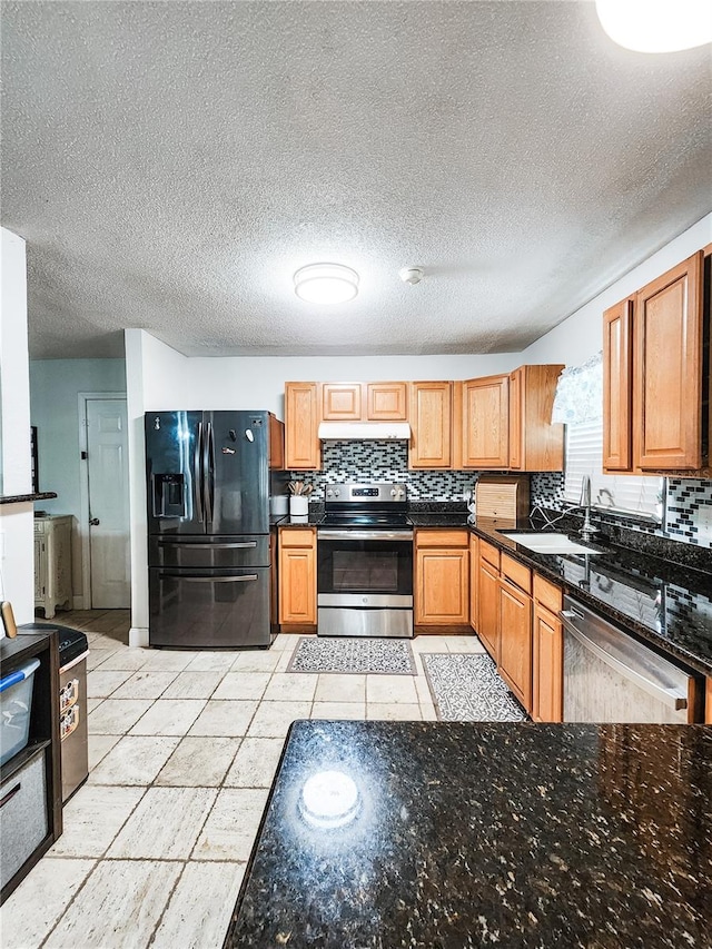 kitchen with a textured ceiling, appliances with stainless steel finishes, sink, and decorative backsplash