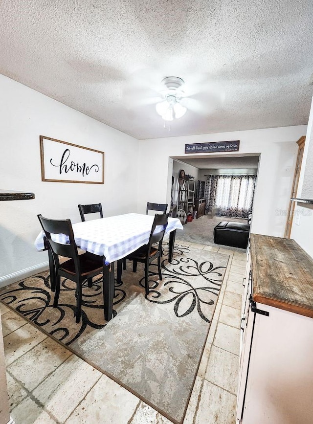 dining area featuring ceiling fan and a textured ceiling