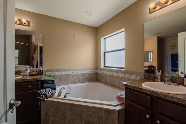 bathroom featuring vanity and a relaxing tiled tub