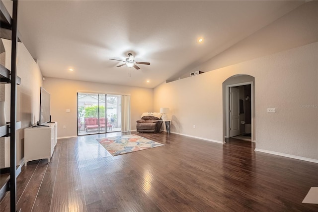 unfurnished living room featuring arched walkways, lofted ceiling, dark wood-type flooring, ceiling fan, and baseboards