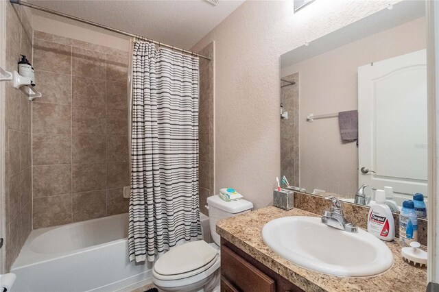 full bath with shower / tub combo, a textured wall, vanity, and toilet