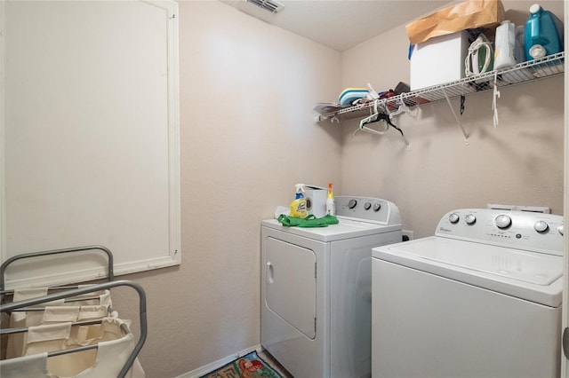 washroom with laundry area, separate washer and dryer, visible vents, and baseboards