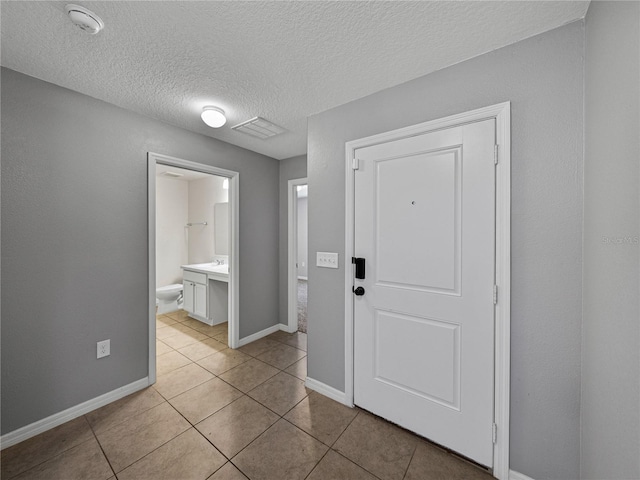 entryway featuring a textured ceiling, light tile patterned floors, and sink