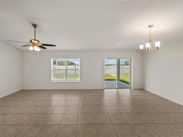 empty room with light tile patterned floors, ceiling fan with notable chandelier, and a textured ceiling