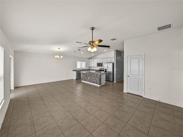 unfurnished living room featuring dark tile patterned floors, vaulted ceiling, and ceiling fan with notable chandelier