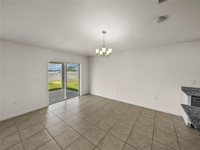 tiled spare room featuring a textured ceiling and a chandelier