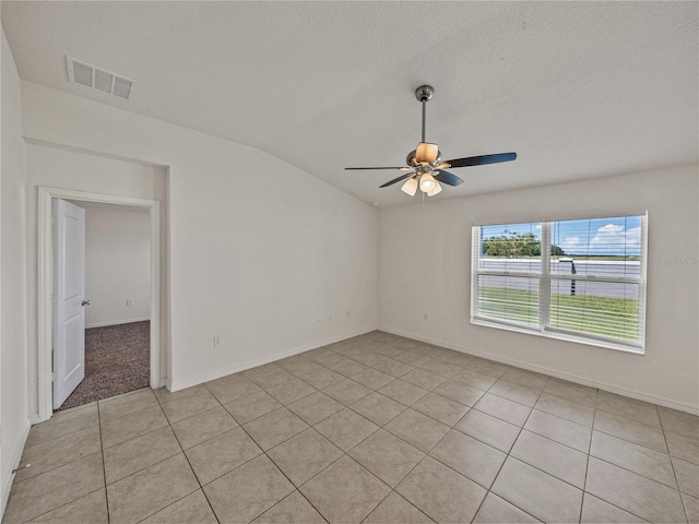 spare room featuring ceiling fan, light tile patterned floors, and a textured ceiling