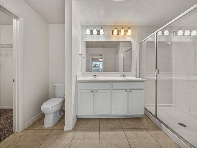 bathroom featuring a textured ceiling, an enclosed shower, tile patterned flooring, vanity, and toilet