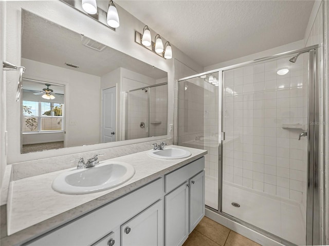 bathroom featuring vanity, tile patterned flooring, a shower with door, and a textured ceiling