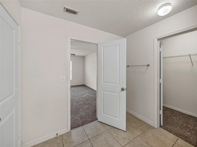 unfurnished bedroom with light carpet, a closet, and a textured ceiling