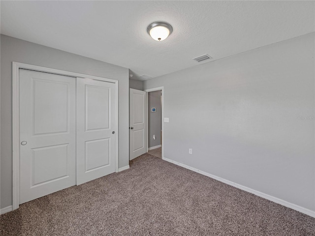 unfurnished bedroom with a textured ceiling, a closet, and carpet floors