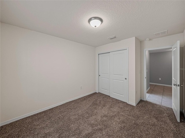 unfurnished bedroom featuring dark carpet, a closet, and a textured ceiling